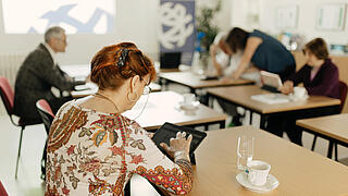 man sieht mehrere ältere Menschen an digitalen Endgeräten