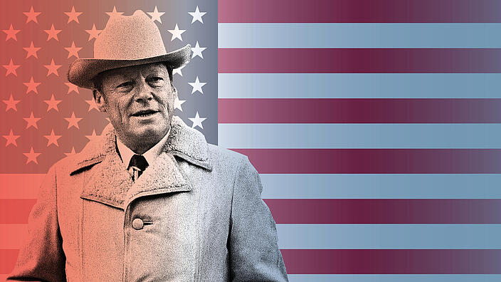 Willy Brandt steht mit Mantel und Cowboyhut vor einer Flagge der USA