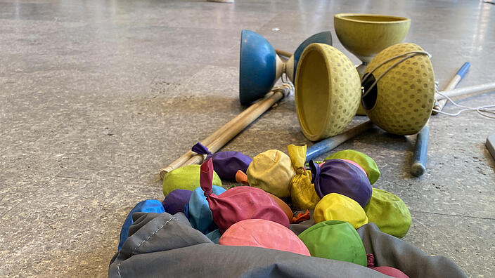 Jonglierbälle und Diabolos auf dem Boden ligend mit seispringenden Kindern im Hintergrund