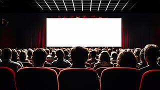 Personen im Kinosaal vor Leinwand