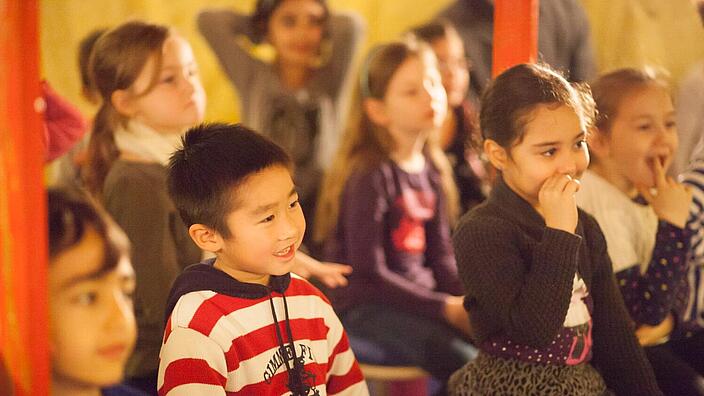 Kinder sitzen gespannt in einer mongolischen Jurte.