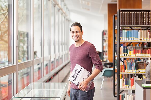 Junger Mann mit Buch Berlin Wedding in der Hand im Lesesaal der Berlin-Studien