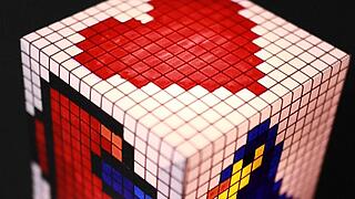 Ein leuchtender Pixelartwürfel auf dem ein rotes Herz zu sehen ist