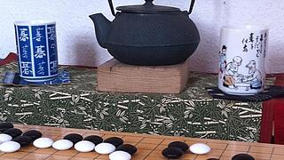 Eine Teekanne mit Tassen und davor ein Go Spiel.