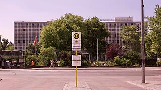 Foto einer Straßenkreuzung mit Bushalteschild im Vordergrund und der Amerika-Gedenkbibliothek im Hintergrund.