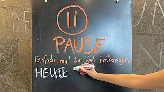 Hand schreibt mit Kreidestift auf Tafel - Pause