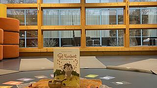 Yogamatten im Kreis, in der Mitte eine Klangschale und ein Buch